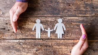 família em papel e duas mãos